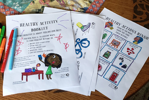 On top of a coffee table sits markers and ZBC's Healthy Activity Booklet pages that have been colored.